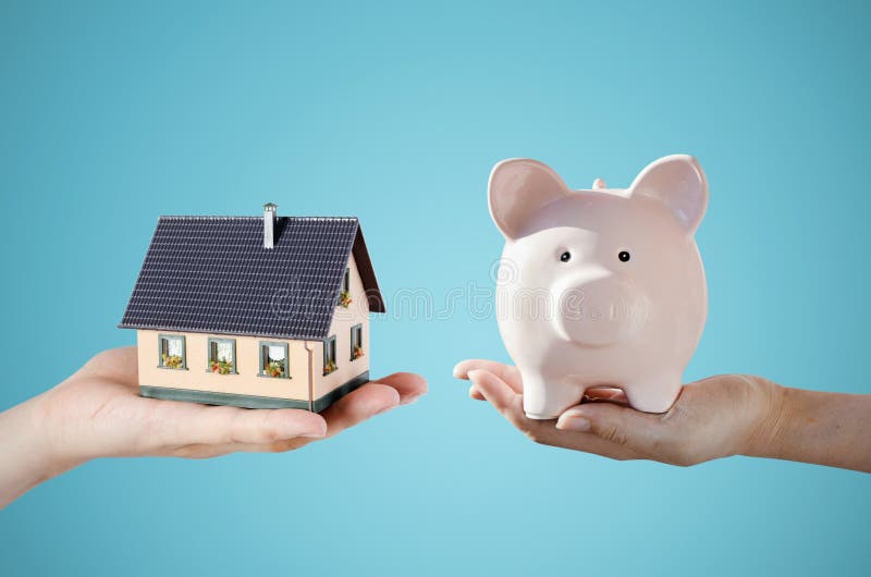 Hand holding house miniature and piggy bank. Home finance concept