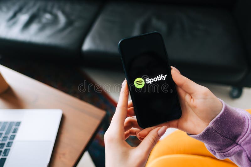 Hand holding iPhone with Spotify app logo on the screen