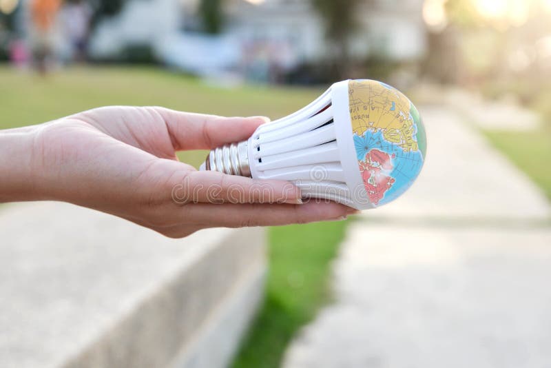 Hand is holding the LED bulb with nature background for save the earth concept stock images