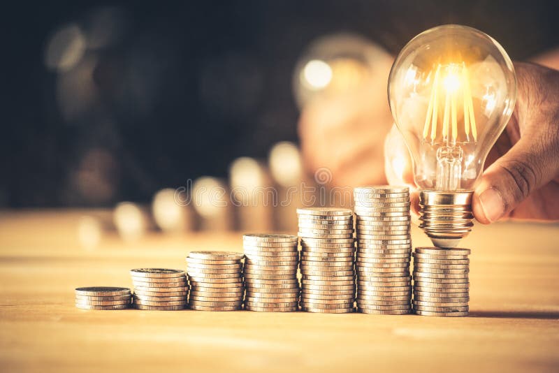 Hand holding a light bulb with coins stack. Creative ideas for saving money concept. royalty free stock photography
