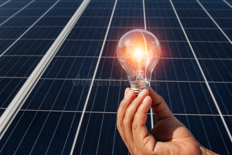 hand holding lightbulb on solar panel concept clean energy in nature