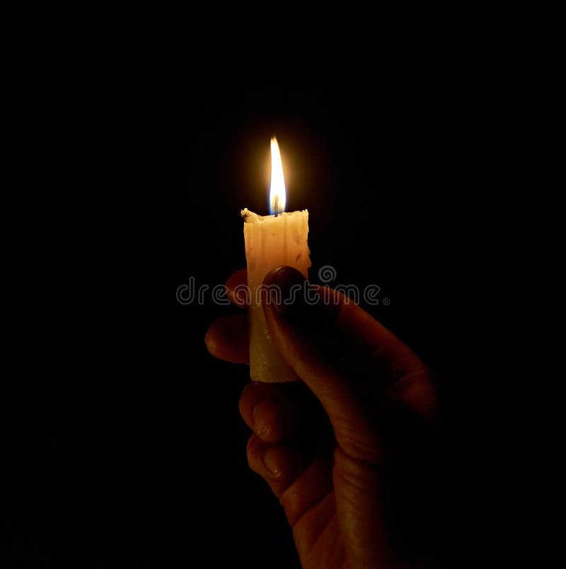 A Hand Holding a Lighted Candle in the Dark. the Light of a Burning