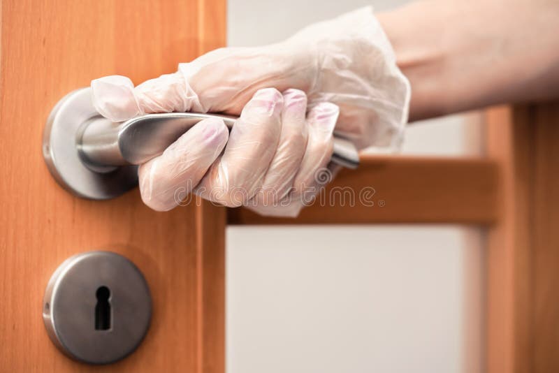 Hand holding metal door handle in gloves - virus spread prevention concept stock photos Hand holding metal door handle in gloves - virus spread prevention concept stock photos