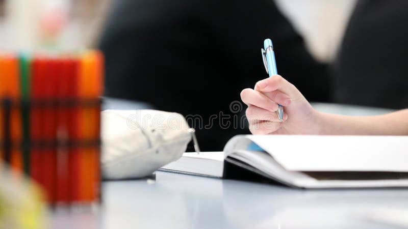 hand holding a pen ready to take notes or write in a book.