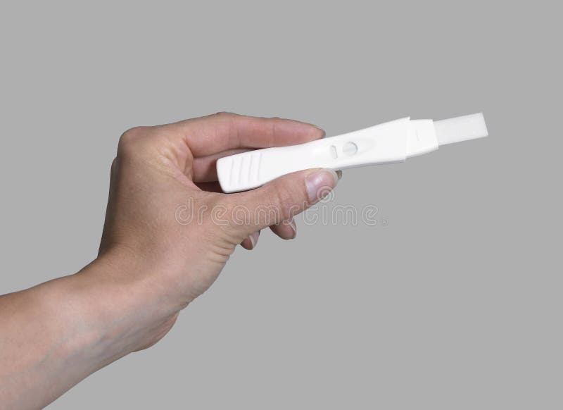 Feminine hand holding a white pregnancy test in grey back. Biological clock stock images, royalty-free photos and pictures