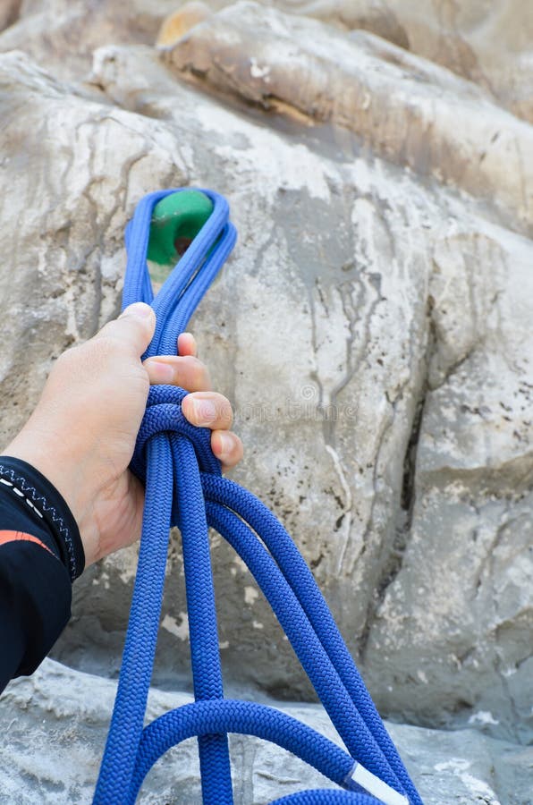 Hand Holding a Rope with Artificial Rock Climbing Wall Stock Photo