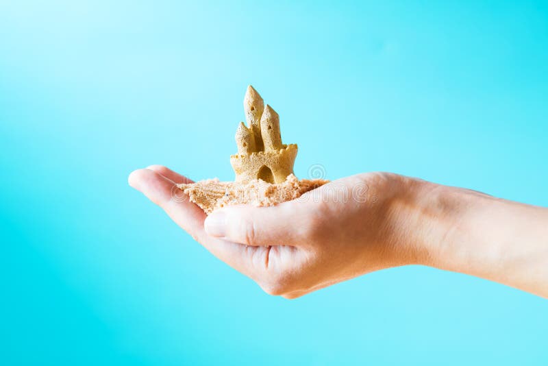 Hand holding a sand castle