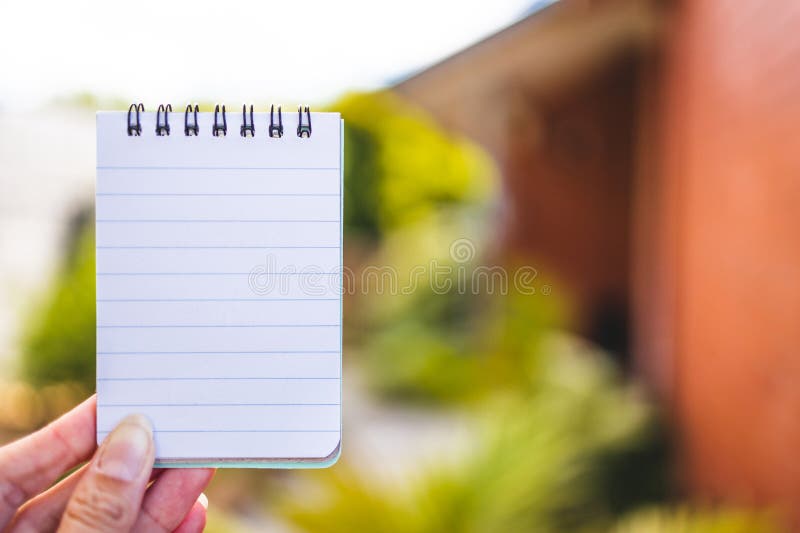 Hand holding small blackboard with blank copy space in front of stylish backyard and house exterior background stock photography Hand holding small blackboard with blank copy space in front of stylish backyard and house exterior background stock photography
