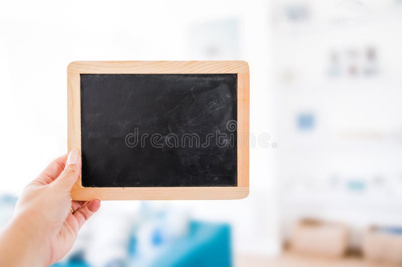 Hand holding small blackboard with blank copy space in front of stylish living room background royalty free stock photography Hand holding small blackboard with blank copy space in front of stylish living room background royalty free stock photography