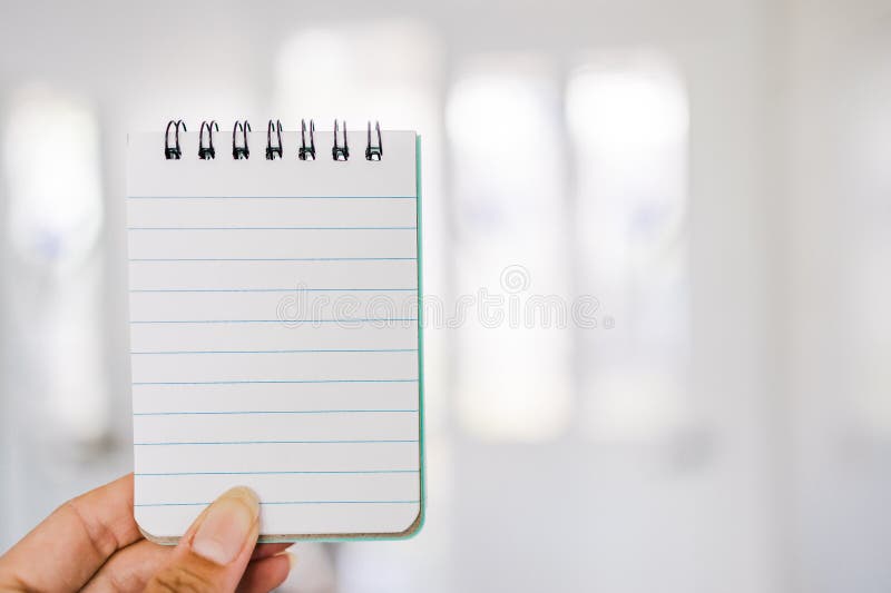 Hand holding small notepad with blank copy space in front of stylish entry door background royalty free stock images Hand holding small notepad with blank copy space in front of stylish entry door background royalty free stock images