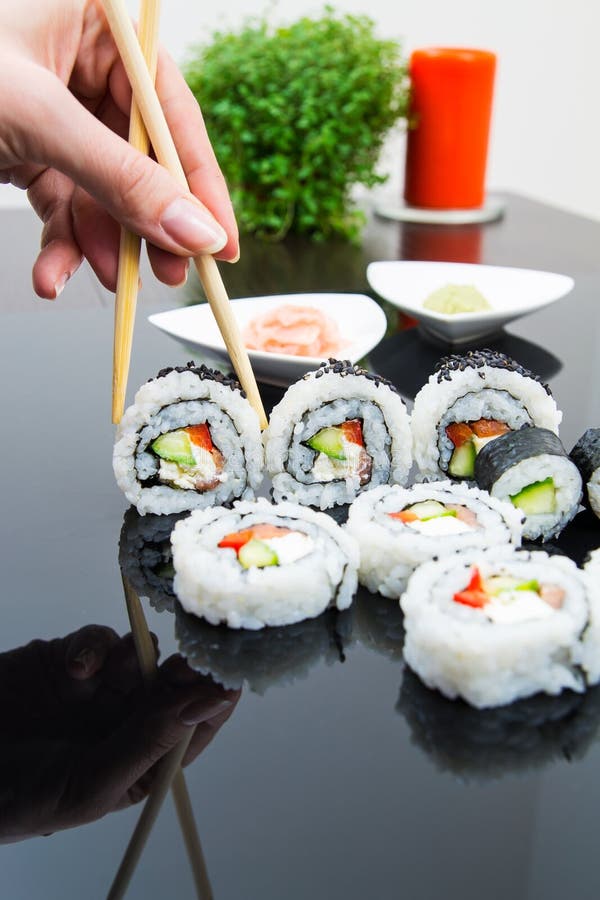 Hand holding stick with maki sushi set