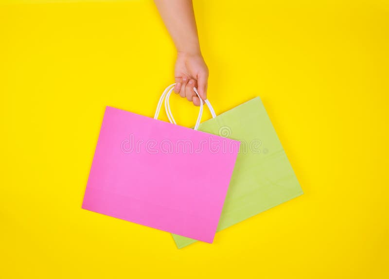 Download Hand Holding Two Paper Shopping Bags On A Yellow Background Stock Image Image Of Consumerism Backdrop 152994777 Yellowimages Mockups