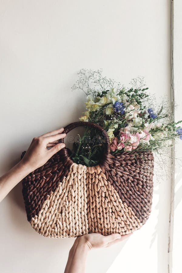 hand holding wildflowers in wicker bag at rustic window. colorful flowers in brown basket in sunlight, space for text. rural stock image hand holding wildflowers in wicker bag at rustic window. colorful flowers in brown basket in sunlight, space for text. rural stock image