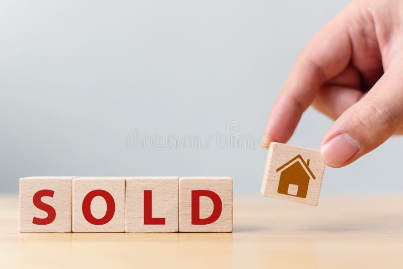 Hand holding wood cube block with icon house and word SOLD. Property investment and house mortgage financial concept