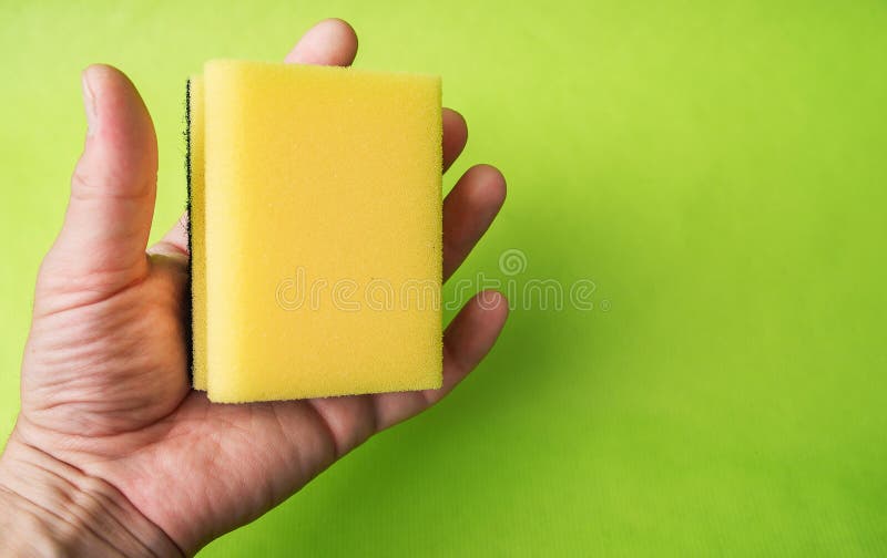 Hand Holds a Kitchen Sponge on a Green Background Stock Image Image