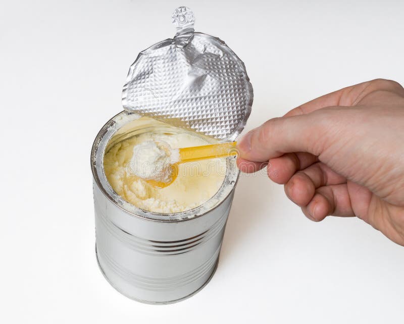 Hand holds scoop with baby milk formula royalty free stock photography