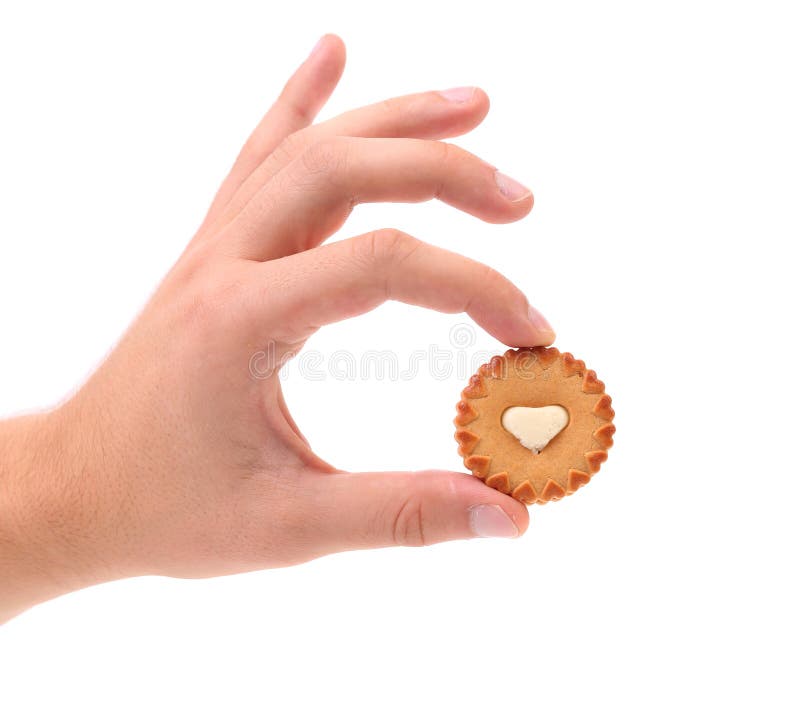 Hand holds sweet pastry with white cream heart.