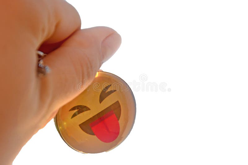 The hand holds a yellow keychain against the white background . Smile shows tongue, carefree joyful life. royalty free stock photos The hand holds a yellow keychain against the white background . Smile shows tongue, carefree joyful life. royalty free stock photos