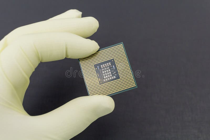 Hand i den? tsittande gula handsken som rymmer en mikrochips f? r CPU-datorprocessor fotografering för bildbyråer