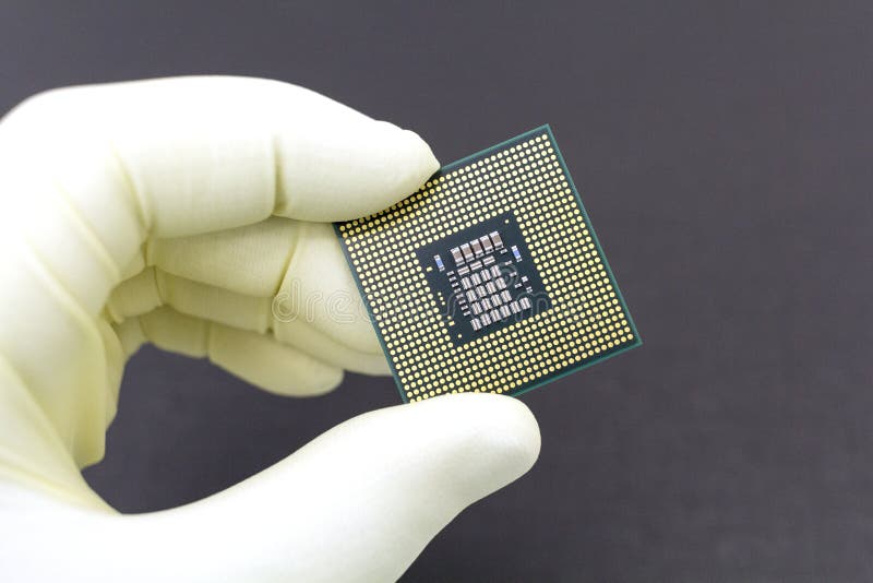Hand i den? tsittande gula handsken som rymmer en mikrochips f? r CPU-datorprocessor royaltyfri fotografi