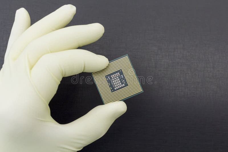 Hand i den? tsittande gula handsken som rymmer en mikrochips f? r CPU-datorprocessor arkivbild