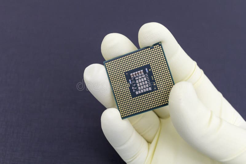 Hand i den? tsittande gula handsken som rymmer en mikrochips f? r CPU-datorprocessor arkivfoto