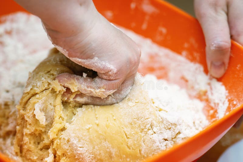 Hand kneading honey cookie dough orange plastic bowl. Homemade baking process royalty free stock photography