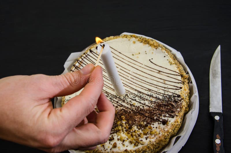 Hand lights a candle on a cake. stock photo Hand lights a candle on a cake. stock photo
