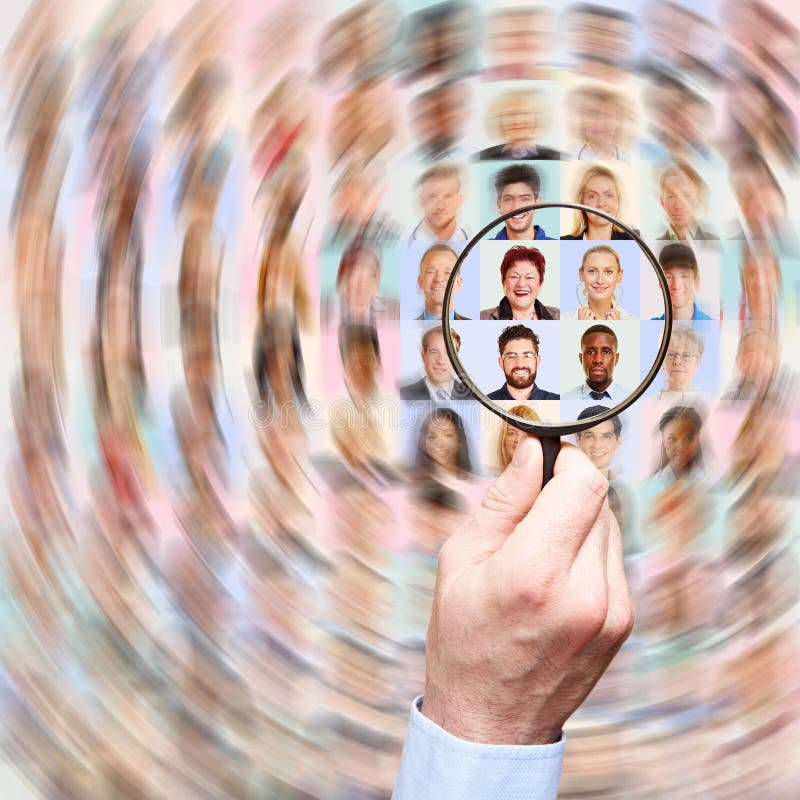 Hand with magnifying glass searches for the right employees in a multitude of portraits royalty free stock photo