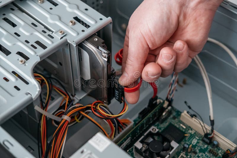 Hand of man plugging SATA Serial AT Attachment, Serial ATA data cable in hard drive device. royalty free stock photography