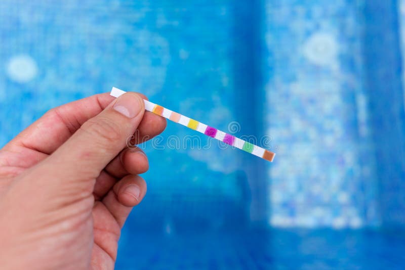 Hand with Measuring Pool Strips To Check Water Quality in a Swimming