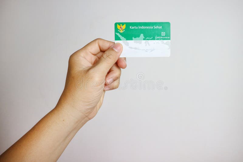 Hand med donesiskt statligt sjukförsäkringskort eller kartu bpjs kesehatan isolerad på vit bakgrund.