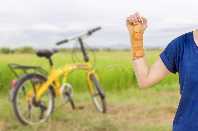 Hand med ett handledstag, ortopedisk utrustning med gul bicycl royaltyfri foto Hand med ett handledstag, ortopedisk utrustning med gul bicycl royaltyfri foto