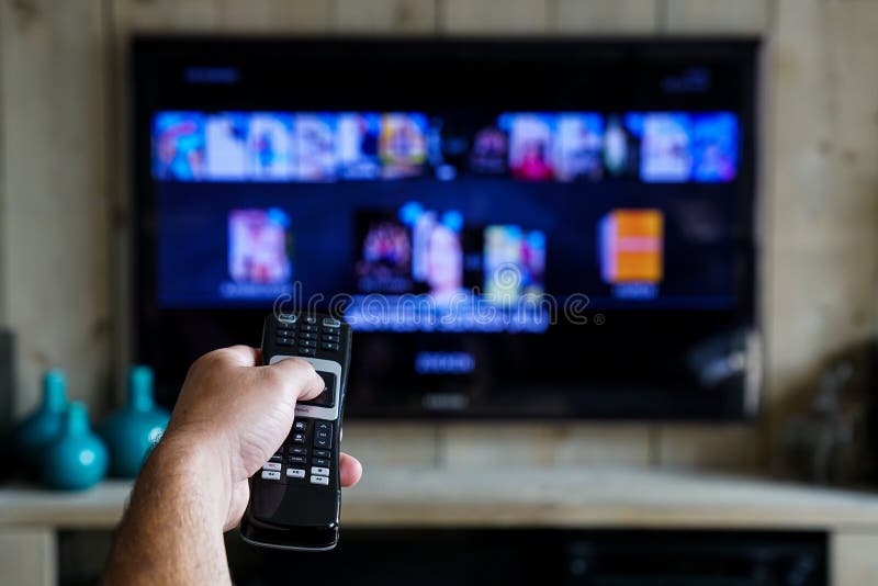 Hand mit einem Fernsteuerungs Was im Fernsehen ist und schiebt durch apps en-Filme im Ihrem Fernsehen stockbilder