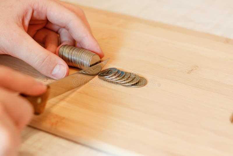 Hand mit einem Messer, das einen Stapel der Münze schneidet Konzept von Etatverkürzungen stockbilder Hand mit einem Messer, das einen Stapel der Münze schneidet Konzept von Etatverkürzungen stockbilder