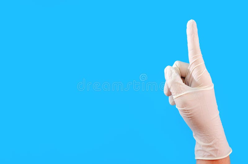 Hand mit weißem Gummischutzhandschuh auf dem blauen Hintergrundgestikulieren. Gestensprache zeigt onecopy Raum. stockfotos