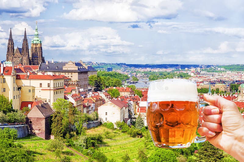 Hand with a mug of beer on the background of the panorama of Prague