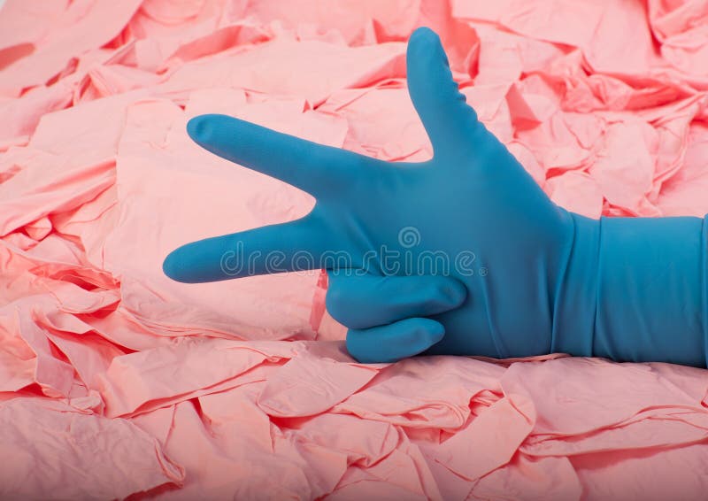 Hand in new blue latex medical glove on background of a lot pink rubber gloves