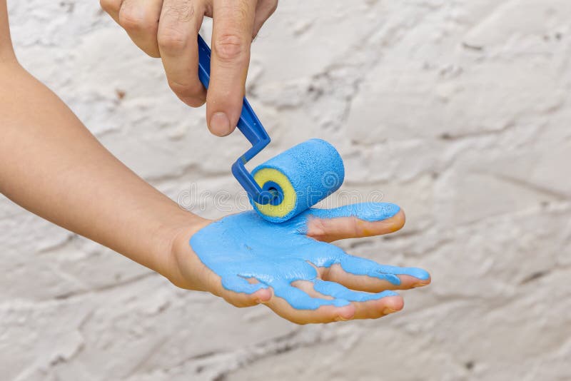 The Hand is Painted with a Roller in Blue. Stock Photo Image of