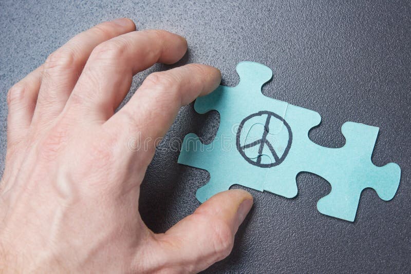 Hand of person collects puzzle with symbol of pacifism. Peace sign on puzzle. World Day of Peace concept. royalty free stock photo Hand of person collects puzzle with symbol of pacifism. Peace sign on puzzle. World Day of Peace concept. royalty free stock photo