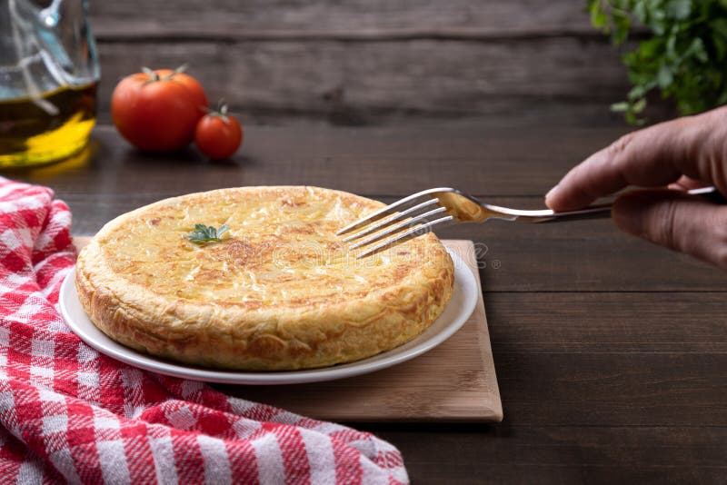 Hand Picking Up Spanish Omelette with Fork on Rustic Background