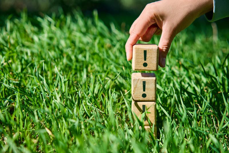 Hand placing wooden cube with exclamation mark symbol on pyramid stack royalty free stock photos