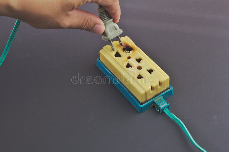 The hand is plugging in the power cord, the trailer plug, the short circuit causing a new fire. The fire was caused by a short circuit. Electricity short circuit. Damaged extension cord stock images, royalty-free photos and pictures