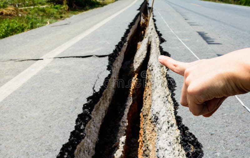 Hand point to cracked road, cracked road aftetr earthquake, Thailand