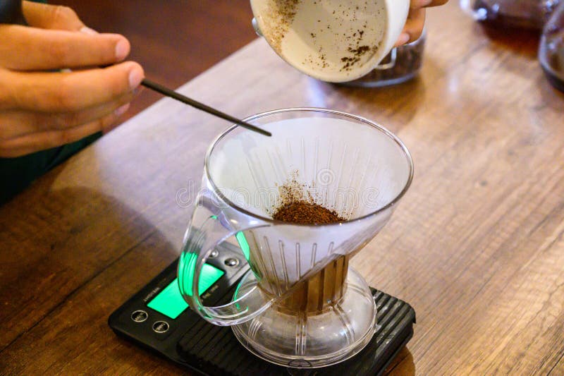Hand pouring fresh coffee grounds for pour over brewing royalty free stock image