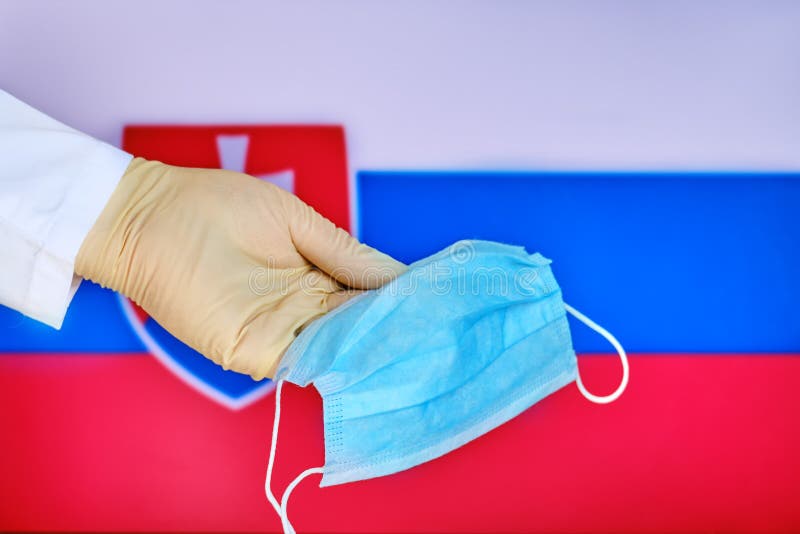 Hand in a protective glove with a medical mask on the background of the Slovakia flag, concept coronavirus epidemic. Doctor holds