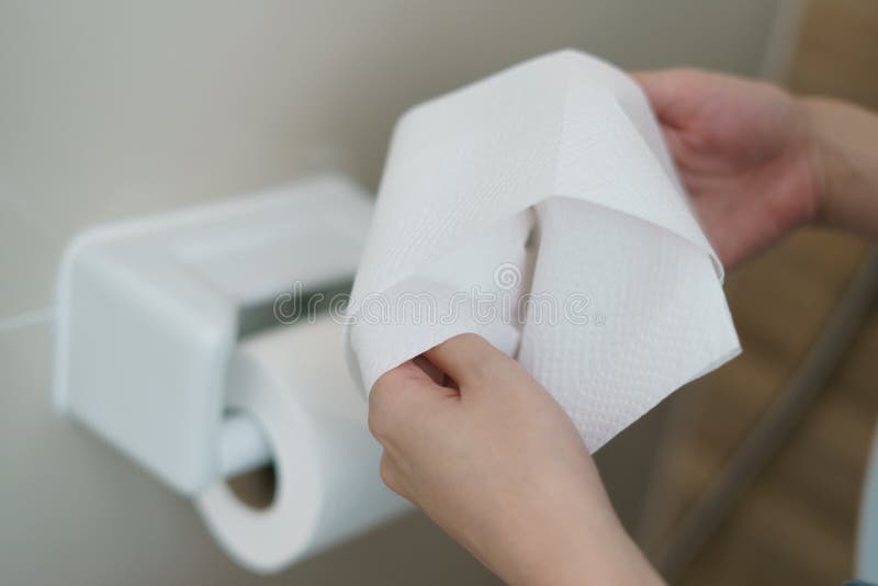 Hand pulling a roll of toilet paper tissue