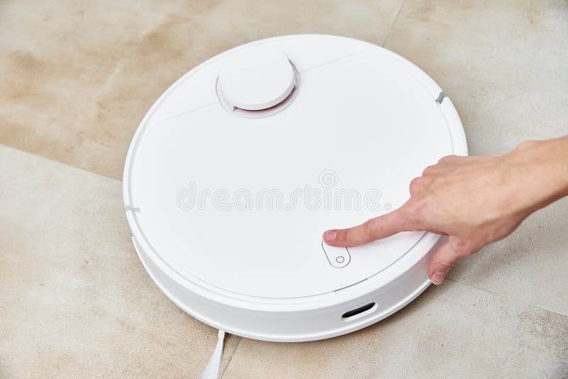 Hand Push Start Button on Robot Vacuum Cleaner. Modern Smart Household