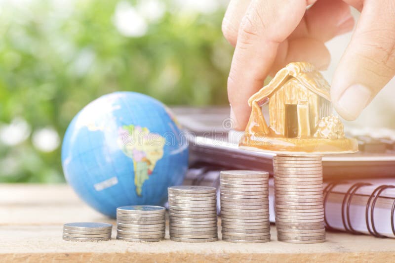 Hand put money on pile of coins, globe and house, concept in growth, sell, buy, save and invest in business of home stock photo Hand put money on pile of coins, globe and house, concept in growth, sell, buy, save and invest in business of home stock photo