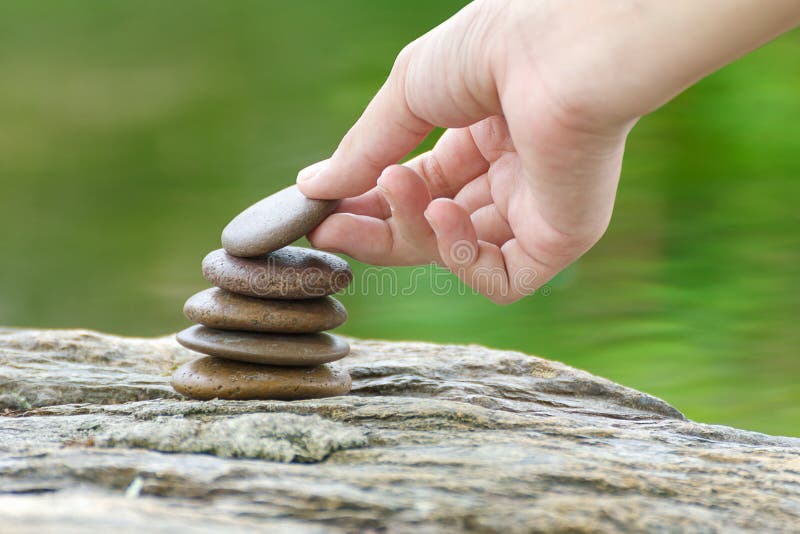 Hand put stone building a pile of zen stones